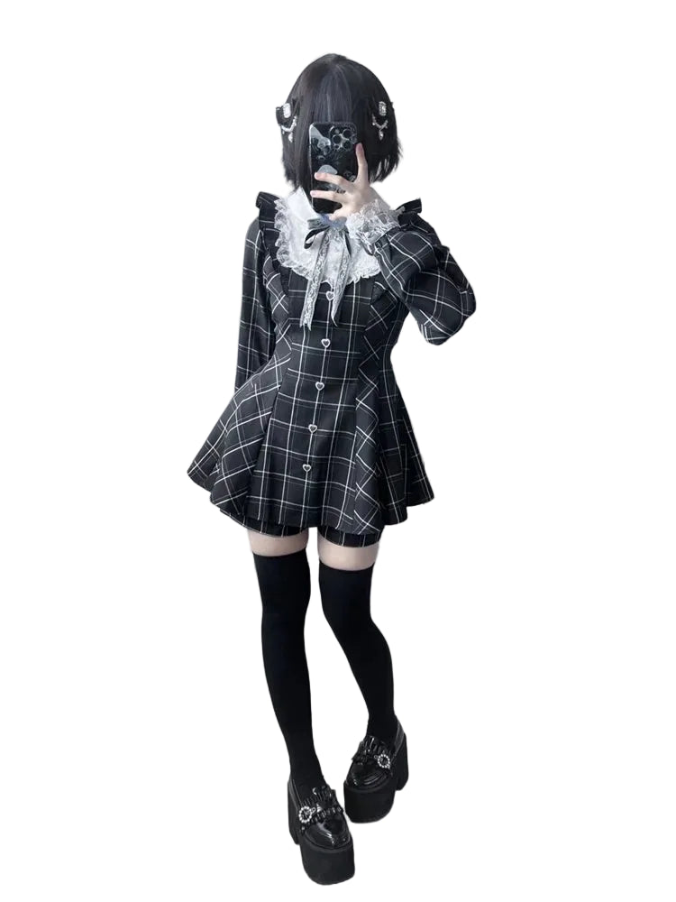 A person modeling a black and white plaid mini dress costume with a large white ruffled collar, black thigh-high socks, and black platform shoes with silver hardware, posed against a plain white background.