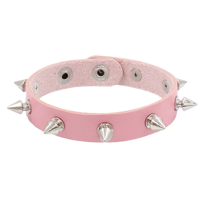 Slim pink PU leather cuff with a single row of silver cone spikes.