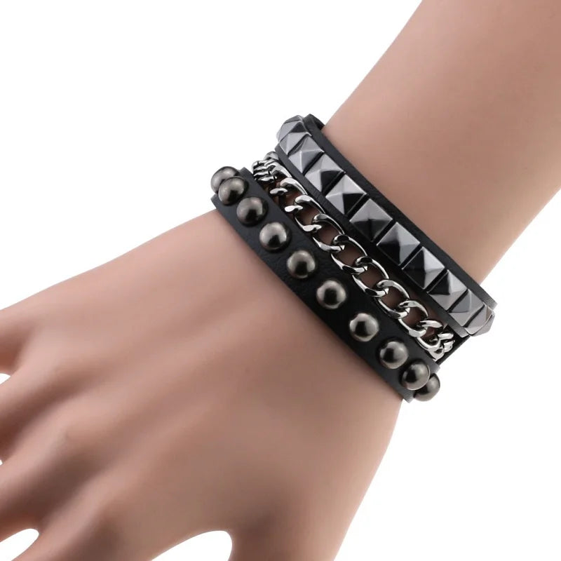 Black PU leather cuff with a layered look: a row of dome studs, a silver curb chain, and a row of dark pyramid studs.