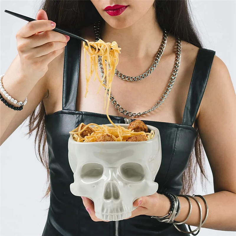 A glazed ceramic bowl shaped like a skull, with an open top and a smooth off-white finish.