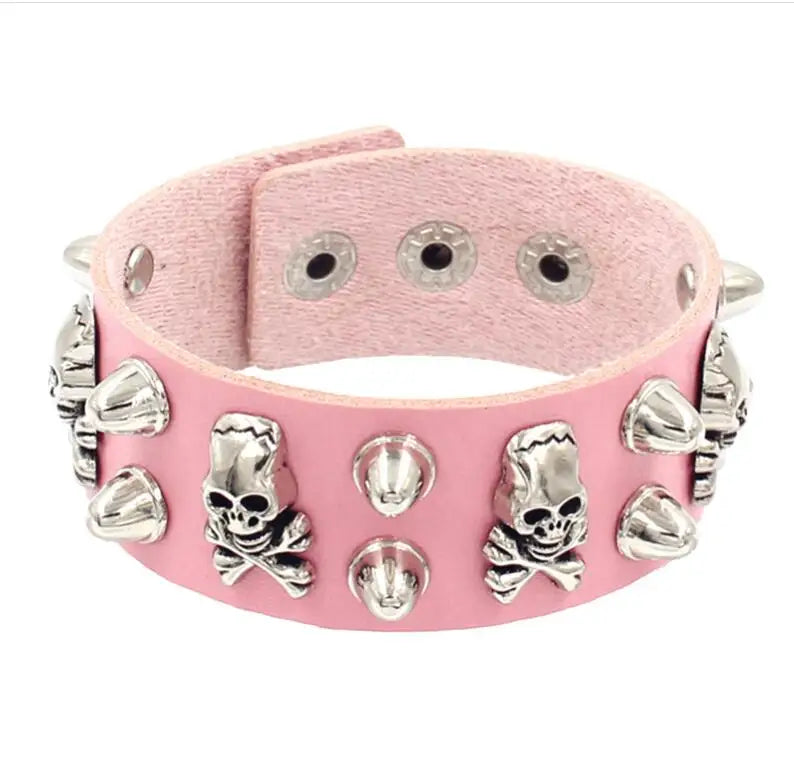 Pink PU leather cuff with silver skull-and-crossbones studs alternating with cone spikes.