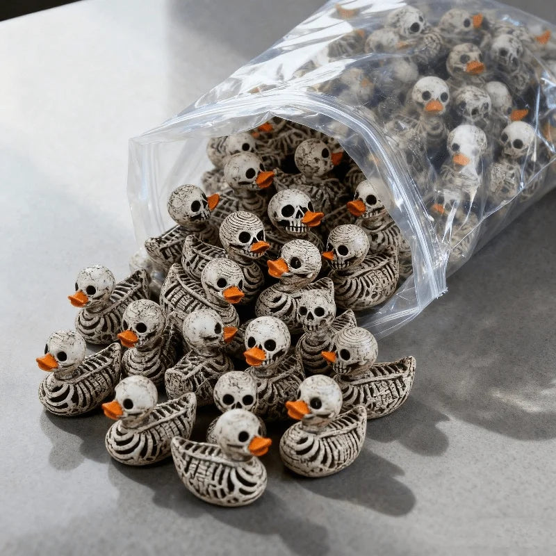 A collection of tiny bone-white skeleton duck resin figurines with orange beaks and skull detailing, shown spilling from a clear plastic bag.