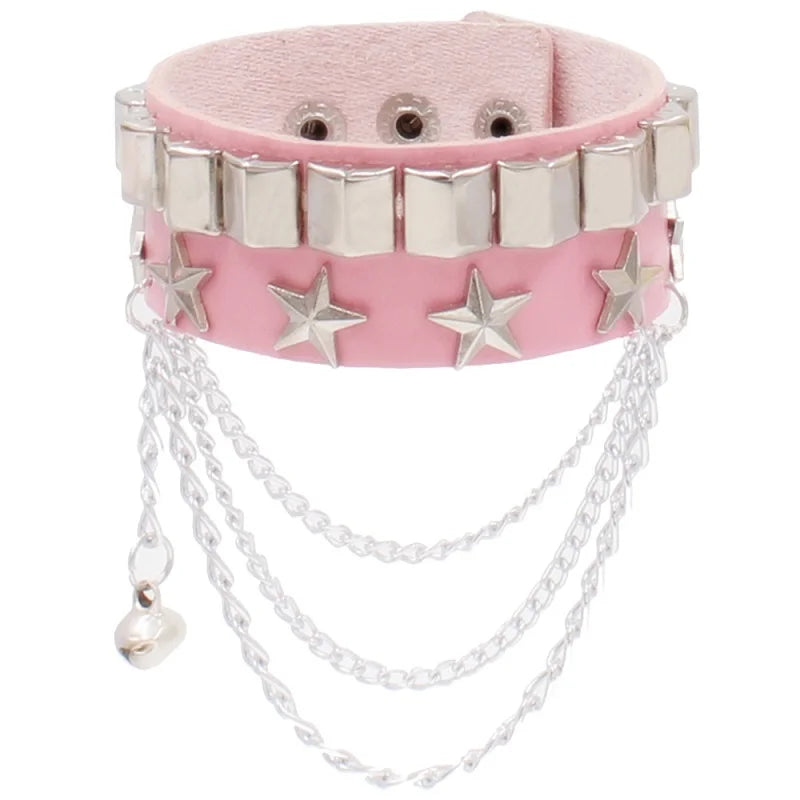 Pink PU leather cuff with a row of silver pyramid studs and a row of silver stars, finished with draped silver chains and a small bell charm.